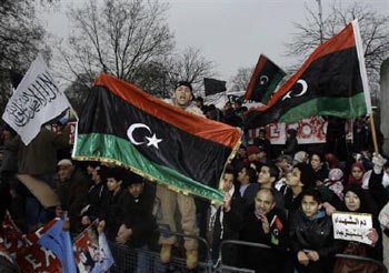 تظاهرات در جلو سفارت لیبی در لندن با پرچم قدیمی- اینگونه هماهنگی و همایش در برابر بیشتر سفارت خانه های لیبی در سراسر جهان برپا بوده، و همچنین ادامه دارد.