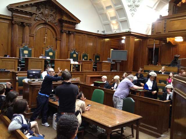 یک صحنه از نشست دادگاه در انگلیس پیش از برگزاری و تشکیل جلسه رسمی. درست با دادگاههای ما که در آن یک یا چند آخوند فرومایه و بی سواد دیده می شود، قابل مقایسه است.